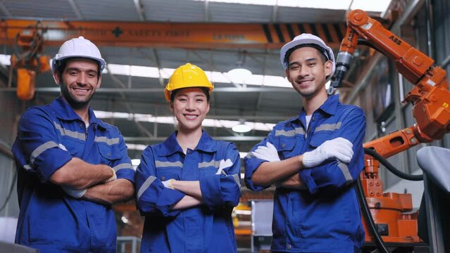 Group of expert Engineer in safety uniform crossed arms smiling looking at camera have confidence front of welding robot at steel industry. Factory and warehouse concept