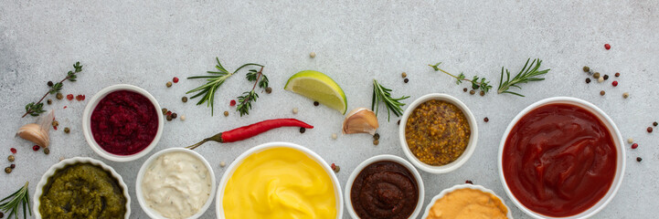 Different types of sauces in bowls with seasonings banner, rosemary and pepper, thyme and garlic, lime and lemon, cilantro, top view, copy space