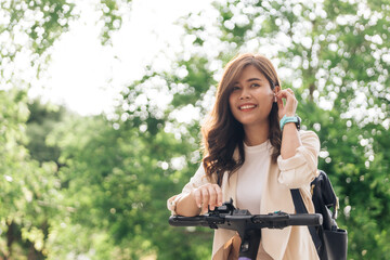 Young asian woman riding a scooter in the park. Healthy lifestyle concept.