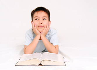 A thinking or daydreaming boy doing homework with glasses, a notebook and a pencil, reading a book highlighted on a white background