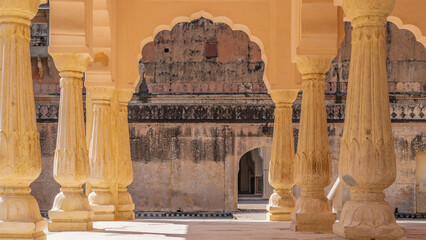 Pavilion in the courtyard of the ancient Amber Fort. Carved sandstone columns, openwork arches against the background of weathered walls. India. Jaipur. 