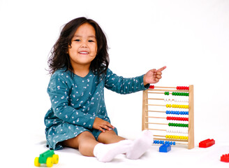 Child sitting on floor playing with wooden Montessori Abacus toy in childrens room. Early math learning through play. Toy counting calculating beads abacus. Educational game. Montessori material.