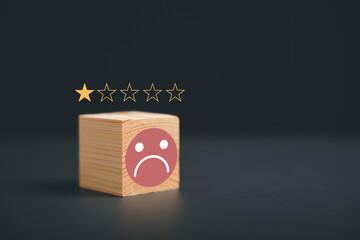 Frown icon on cube wooden block on black background. Customer satisfaction evaluation concept, bad...