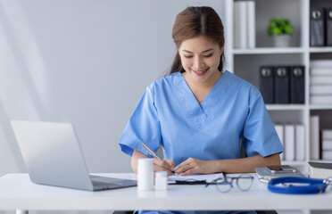 Happy doctor Portrait of young asian woman nurse or doctor smiling using a laptop writing content at consultation
