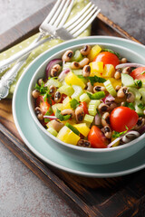 Fresh black-eyed pea salad with tomatoes, celery, pepper, cucumber and onion close-up in a bowl on the table. Vertical