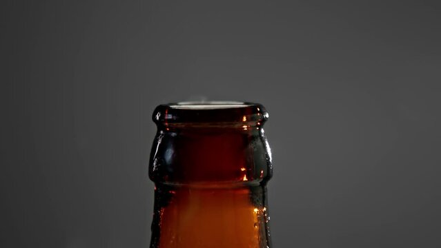 Opening Cap of Full Glass Bottle with Beer Drink Close Up. Drinking Alcohol Beverage at Abstract Modern Party Indoors. Macro View of Open Cover Lid and Beautiful Smoke Isolated in Dark Studio Shot