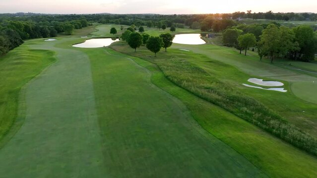 Aerial shot of golf course in USA during summer sunset. Perfect green grass and lakes.