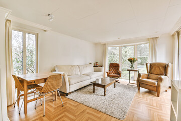 a living room with wood flooring and white couches in the center of the room is a large window