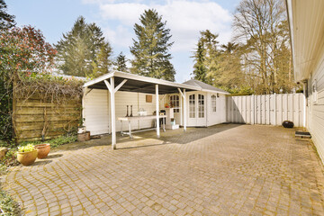 a backyard area with a patio and white fenced in shed, surrounded by trees on either side of the...