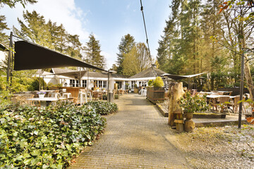 Obraz premium an outside area with tables, chairs and umbrellas on the patio in front of a house surrounded by trees