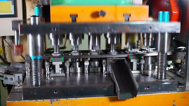 Close up of a punch press forming metal parts in a production line