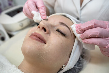 Obraz na płótnie Canvas beautician applies or removes moisturizer from a client's face