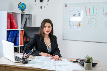 Caucasian businesswoman in suit filling 1040 form of individual income tax return at modern office