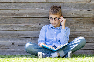 A boy reading a book on a grass