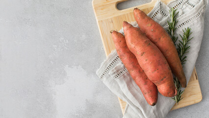 Raw sweet potatoes on cutting board. . Orange kumara, yam. Healthy eating. Copy space