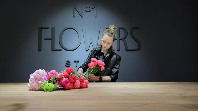 A young woman florist prepares a bouquet of flowers in a shop. Floristry and the concept of small business.