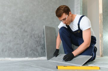 A male construction worker installs a large ceramic tile