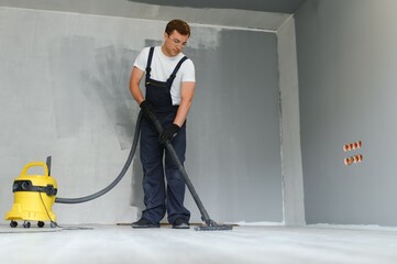 A worker vacuums a room after repairing the floors. Apartment after renovation with a vacuum...