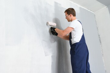 One painter with paint roller making wall prime coating at home repair renovation work.