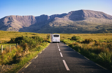 Beautiful landscape scenery with white bus driving on empty scenic road trough nature with...