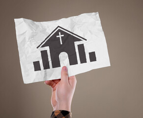 Man holding crumpled paper with illustration of church on pale brown background, closeup