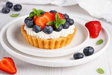 Creamy cheesecake cake with blueberry and strawberries on a light table