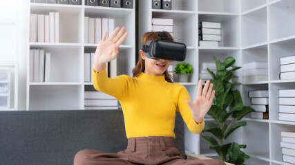 Smiling woman having fun using VR glasses playing game at home happily and enjoy virtual reality.