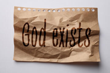Crumpled paper with text God Exists on white background, top view
