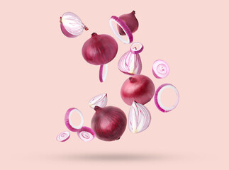 Whole and cut fresh red onions falling on light coral background