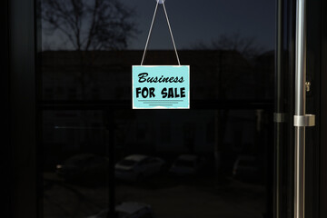Light blue sign with Business For Sale hanging on glass door