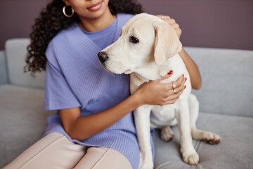 Closeup of black young woman with dog sitting on sofa together