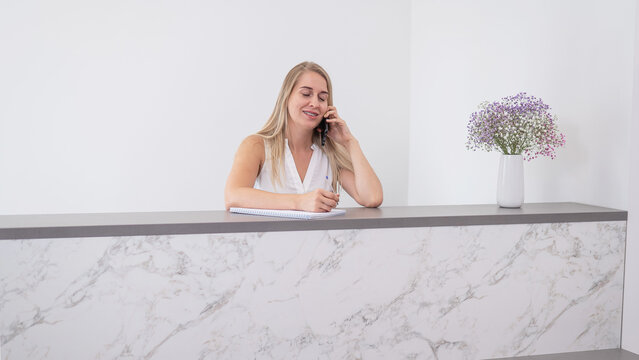 Receptionist in a beauty salon talking to a client on the phone. 