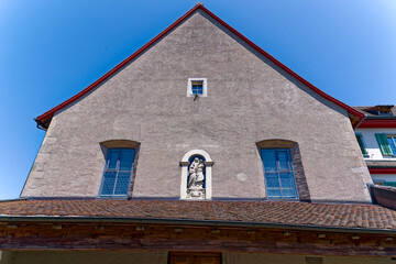 Maria sculpture at facade of historic 		capuchin cloister at the old town of Swiss City of Zug on a sunny spring day. Photo taken May 22nd, 2023, Zug, Switzerland.