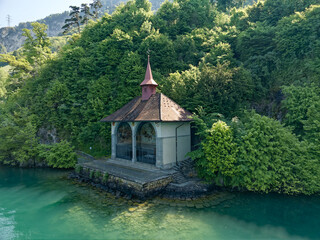Fototapeta na wymiar Famous Tell's Chapel at lakeshore of Lake Uri on a sunny spring day. Photo taken May 22nd, 2023, Sisikon, Canton Uri Switzerland.