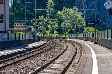 Fototapeta premium Close-up of railway tracks with curve at railway station of village Sisikon on a sunny spring noon. Photo taken May 22nd, 2023, Sisikon, Canton Uri, Switzerland.