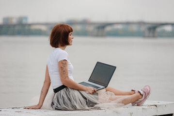 Young girl freelancer working online using laptop and enjoying beautiful nature landscape. convenience that comes with being able to work from anywhere, including in a scenic outdoor location.