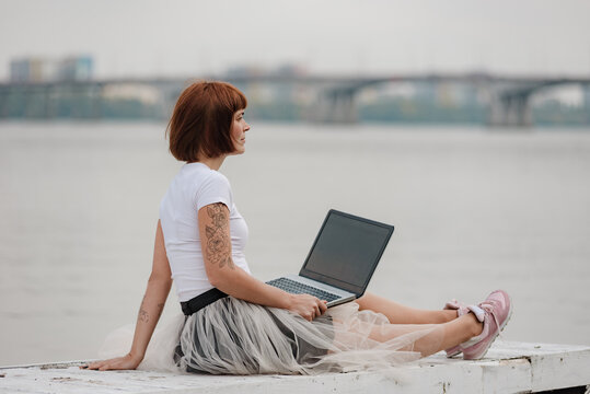 Young girl freelancer working online using laptop and enjoying beautiful nature landscape. convenience that comes with being able to work from anywhere, including in a scenic outdoor location.