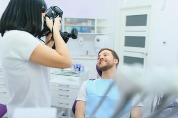 dentist clinic. A female dentist photographing her client's teeth during an appointment at the dental clinic.