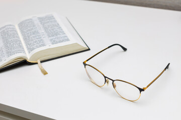 reading glasses lie on the table near the book