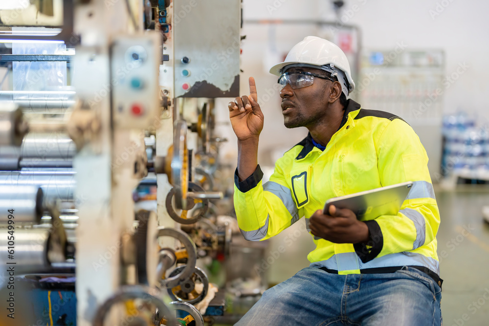 Wall mural african male engineer manager is a mechanic sitting and pointing at steel and plastic manufacturing 