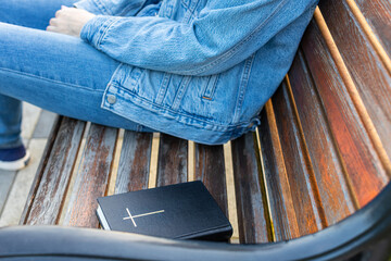 the bible lies on the bench next to the woman.