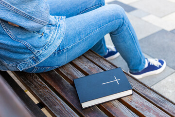 the bible lies on the bench next to the woman.