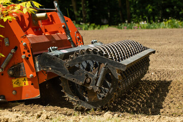 Tractor cultivating the soil with a rotary tiller on the farm.