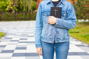 woman holding a bible in her hand standing near the church.