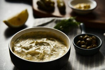 Classic Tartar Sauce with it ingredients on dark stone or marble background. Mayonnaise with dill and pickled cucumbers with lemon. 