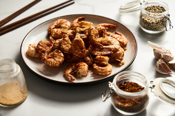 Crispy Pan fried tiger shrimps or prawns with garlic. Chinese or Asian cuisine dish. Shrimps lay on white plate on white marble background. T