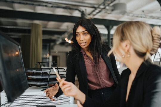 Female entrepreneurs discussing over desktop PC at office