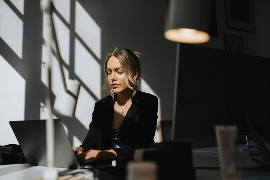 Young businesswoman working on laptop sitting at office