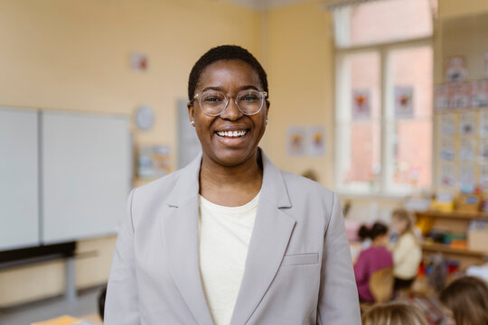 Portrait of happy female teacher wearing blazer in classroom
