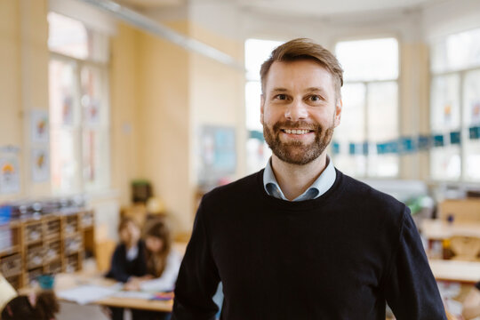 Portrait of smiling male teacher with stubble in classroom